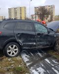 Czarny SUV z uszkodzonym bokiem i otwartą maską na chodniku w krzakach