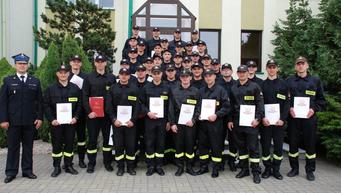 Grupa strażaków pozująca do zdjęcia na zakończenie kursu podstawowego, po lewej kierownik kursu