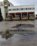 Przed garażem bojowym Szkoły stoją na baczność strażacy ustawieni w półkole, za nimi cztery wozy strażackie, dowódcy pododdziałów oddają honor