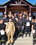 Grupa strażaków pozuje do zdjęcia na zakończenie kursu specjalistycznego w ośrodku szkoleniowym w Tylnej Górze