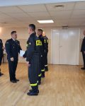 Komendant Szkoły wręcza dyplomy ukończenia kursu grupie strażaków stojących w szeregu, za nim Naczelnik Wydziału Nauczania.