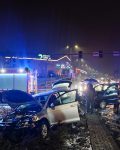 Dwa uszkodzone samochody pomiędzy dwoma wozami strażackimi, pomiędzy samochodami dwóch cywili obok grupy strażaków, w tle galeria Zielone Arkady