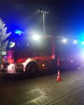 Wóz strażacki z włączonymi światłami z rozłożonym masztem oświetleniowym.