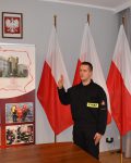 Strażak składa przysięgę, w tle baner Szkoły i trzy flagi Polski
