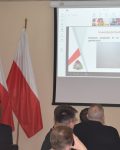 Komendant Szkoły Podoficerskiej prezentuje slajd - Inwestycje budowlane realizowane w 2023 r. Budowa budynku B na poligonie - budynek do ćwiczeń gaśniczych.