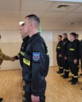 W pierwszym szeregu stoją kursanci, komendant ściska rękę jednemu strażakowi. W tle szereg strażaków .