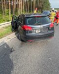 Na drodze tyłem stoi szary samochód osobowy, który uderzył w bariery energochłonne.