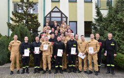 36 strażaków w mundurach koszarowych i służbowych stoją , część z nich trzyma teczki