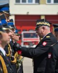 Zastępca komendanta głównego PSP przypina medal jednemu ze strażaków stojących w szeregu
