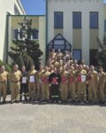20260526_122935 38 strażaków w mundurach koszarowych i służbowych stoją , część z nich trzyma teczki