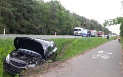 W przydrożnym rowie stoi rozbite auto, w tle droga na której stoją auta.